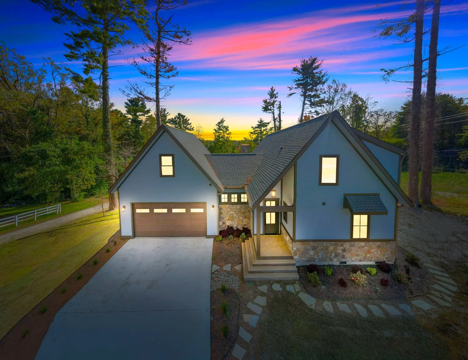 Custom craftsman home at dusk with stone accents and lit windows, Asheville NC