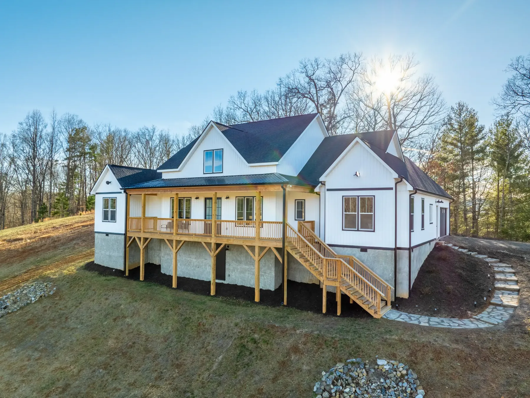 Modern white farmhouse with a wrap-around porch on a hillside lot, Weaverville NC