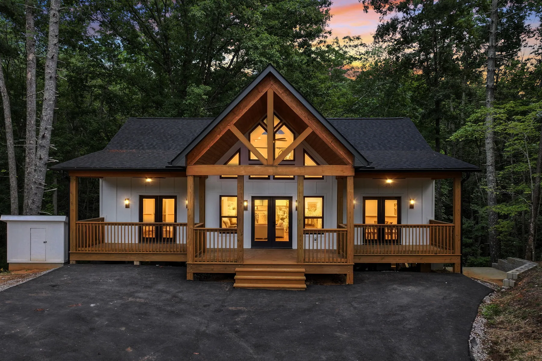 Custom timber-frame home at dusk with glowing windows and a covered porch, Lake Lure NC