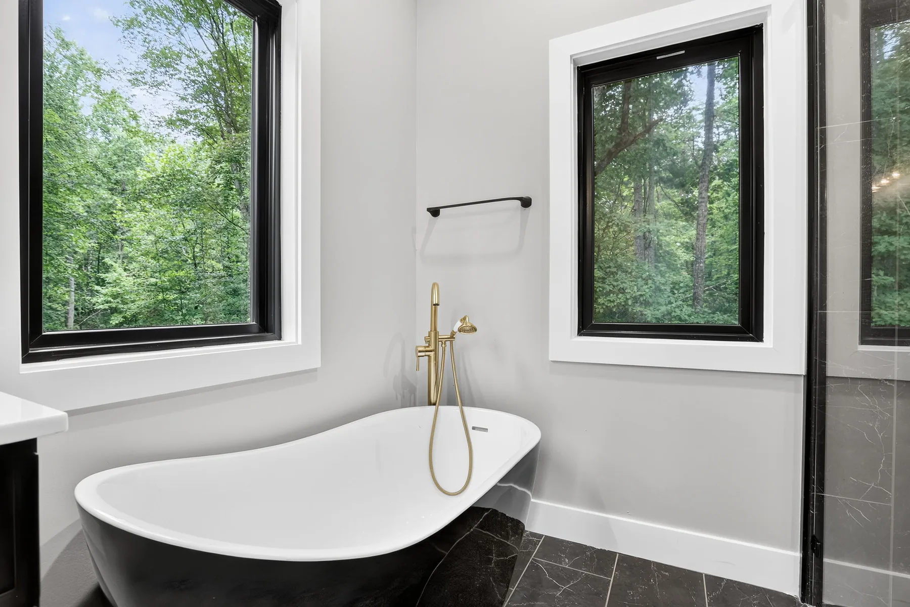 Freestanding soaking tub with a brass floor filler and tiled surround